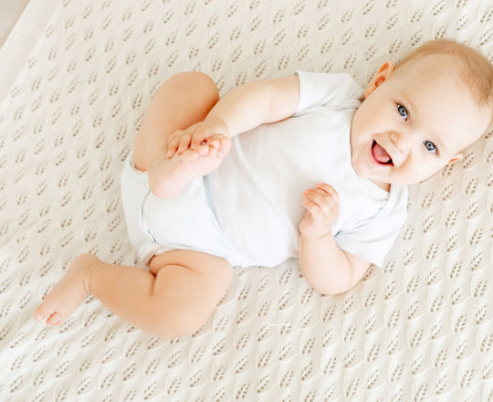 Baby liegt auf einer Decke und lächelt